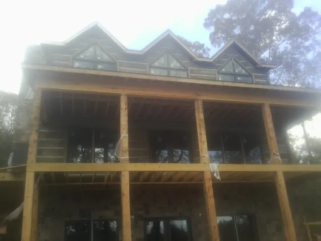 Dormers and porch framing on a large log home under construction — Roof Coating work by our crew in Independence