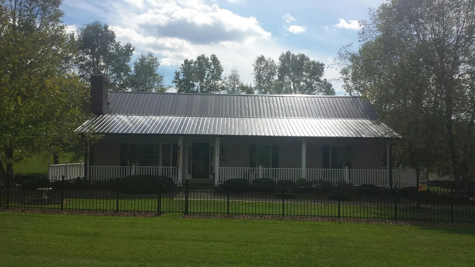Gray metal roof on a brick ranch with a full width front porch — Gutter Guard Installation work by our crew in Independence